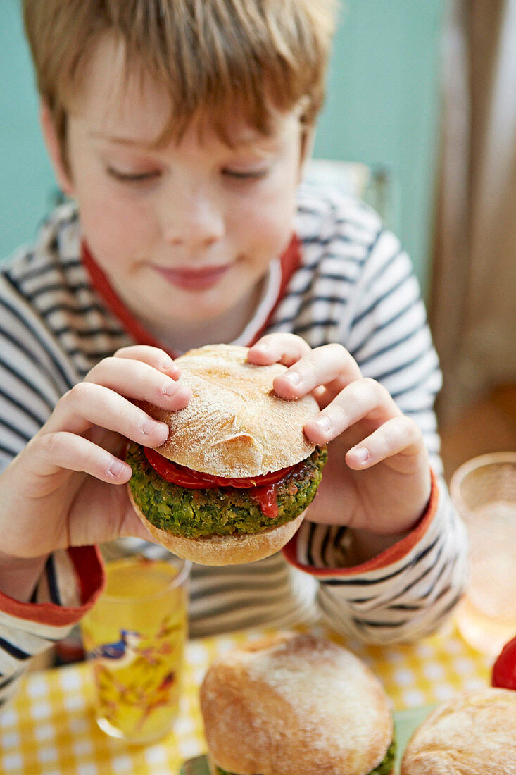 Junge isst grünen Burger