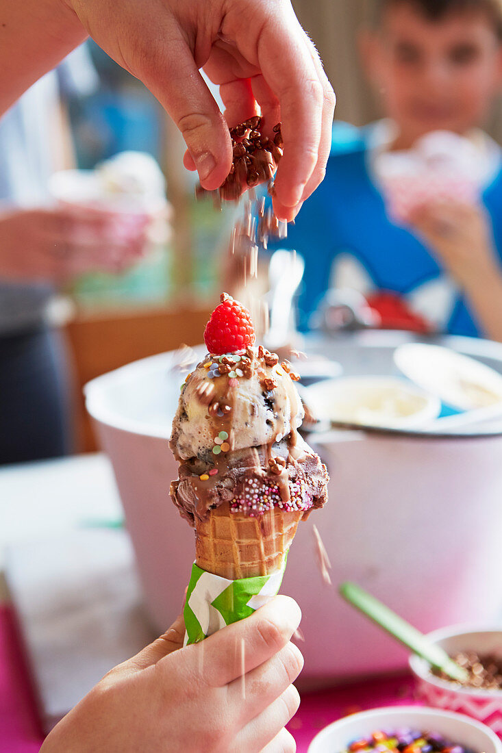 Kind bestreut Eiswaffel mit Zuckerperlen