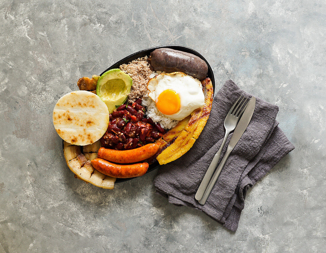 Bandeja Paisa - Bohneneintopf mit Chicharron, Wurst, Arepa, Banane, Avocado, Ei und Reis (Kolumbien)