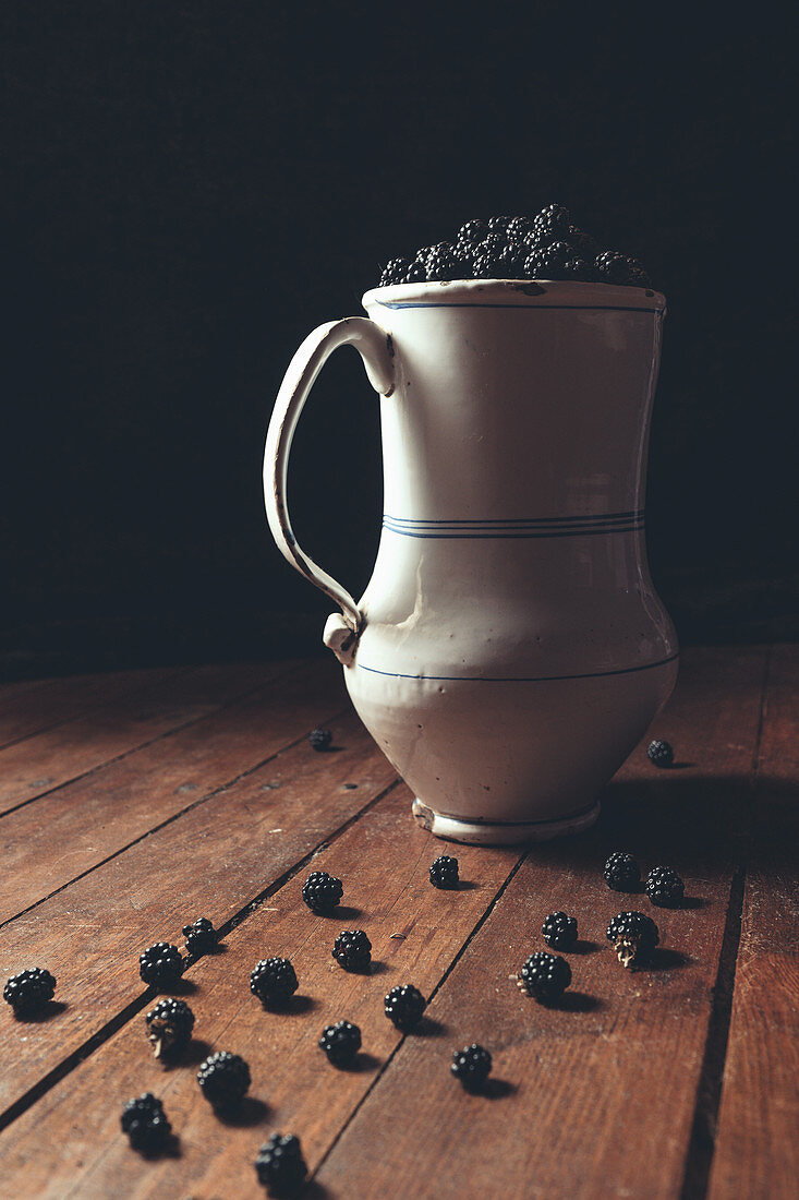 Vintage-Krug mit reifen Brombeeren auf Holzuntergrund