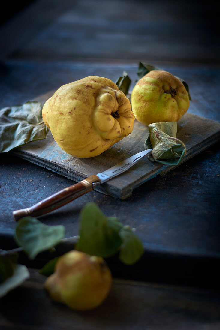 Quinces with a knife on a wooden board
