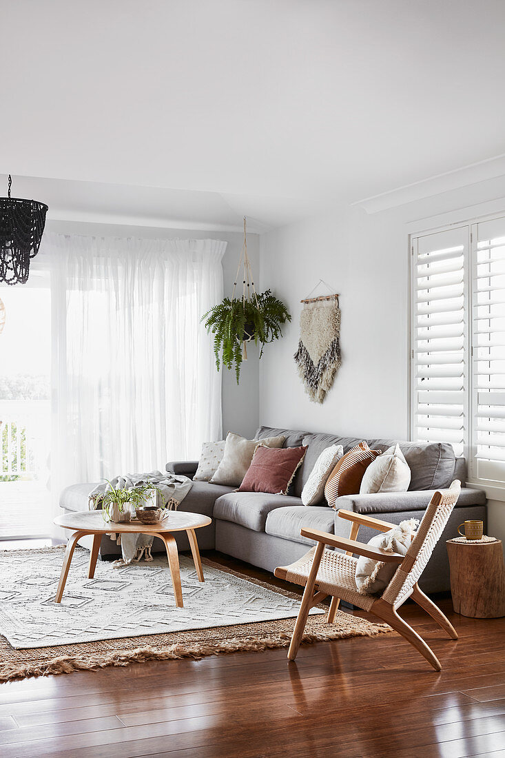 Hellgraues Polstersofa mit Kissen, Sessel und Couchtisch im Wohnzimmer