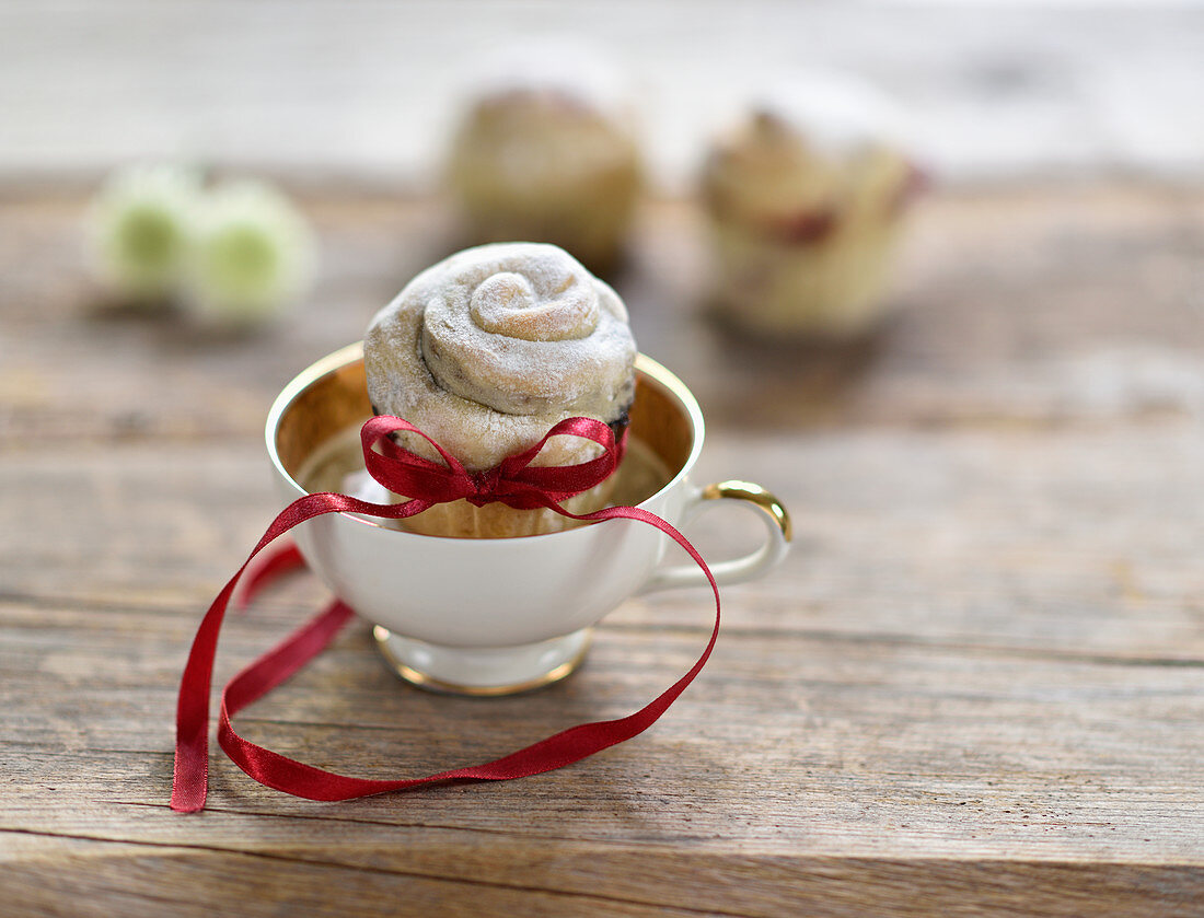 A vegan bun filled with blackcurrant jam in a cup with a golden rim