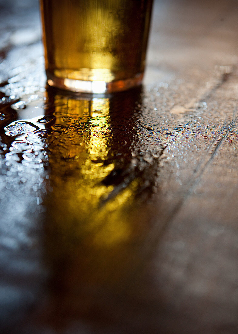 Bierglas auf nassem Holztisch