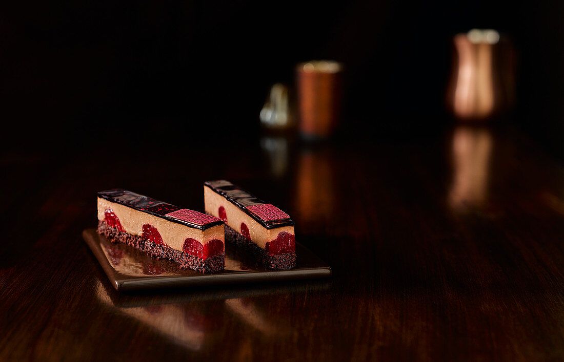 Tonka-Schokoladencremeschnitte mit Himbeeren vor dunklem Hintergrund