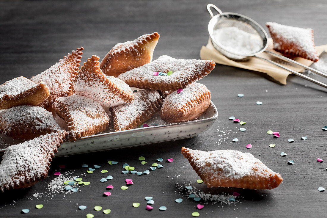 Muzen (German Karneval pastries) with icing sugar and confetti