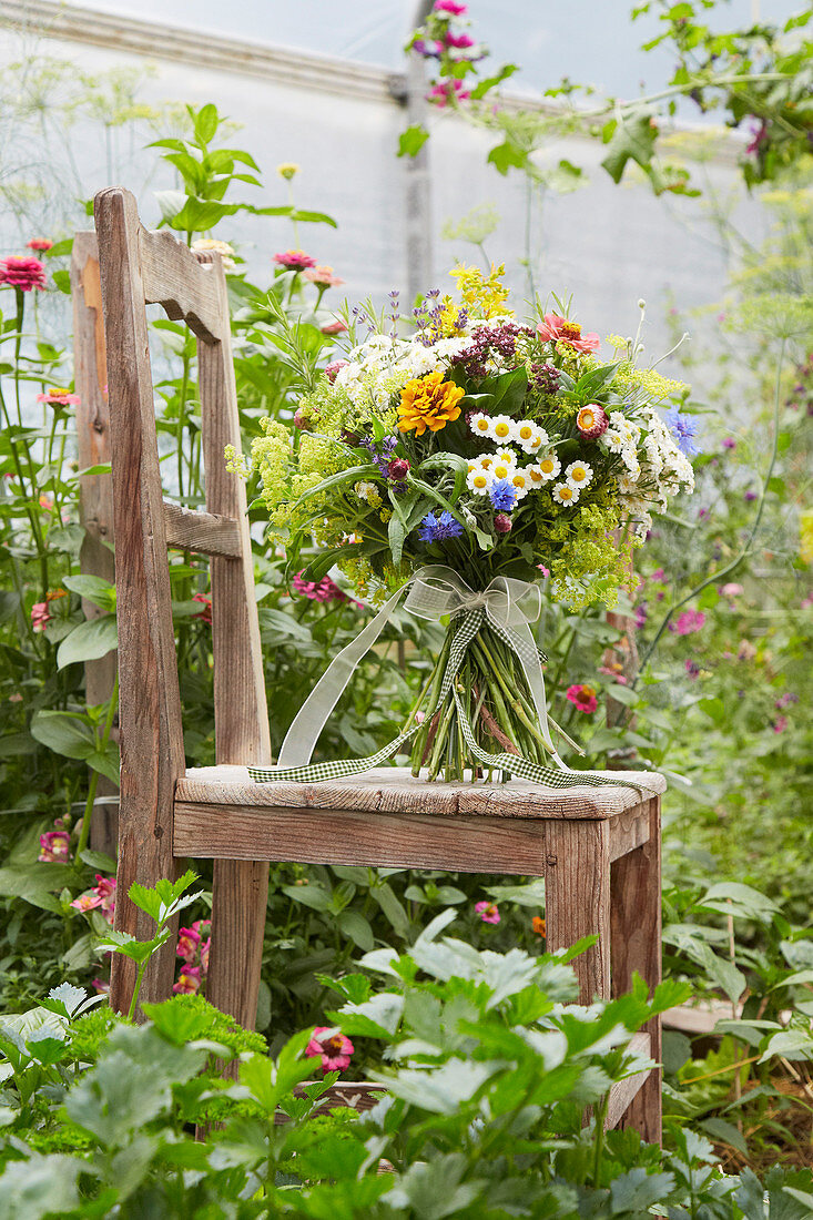 Summer bouquet standing on chair in greenhouse