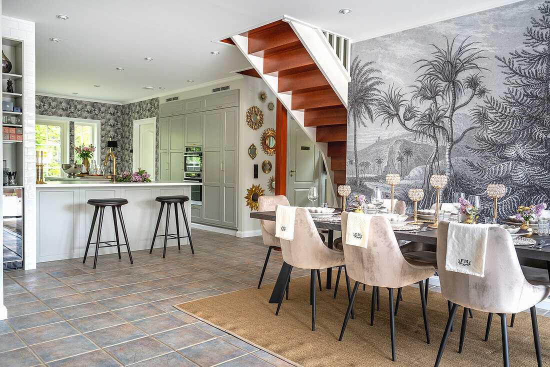 Set dining table with upholstered chairs in front of monochrome mural wallpaper