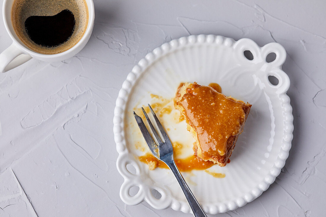 Half eaten slice of Tres Leches cake, covered with caramel sauce and sprinkled with sea salt