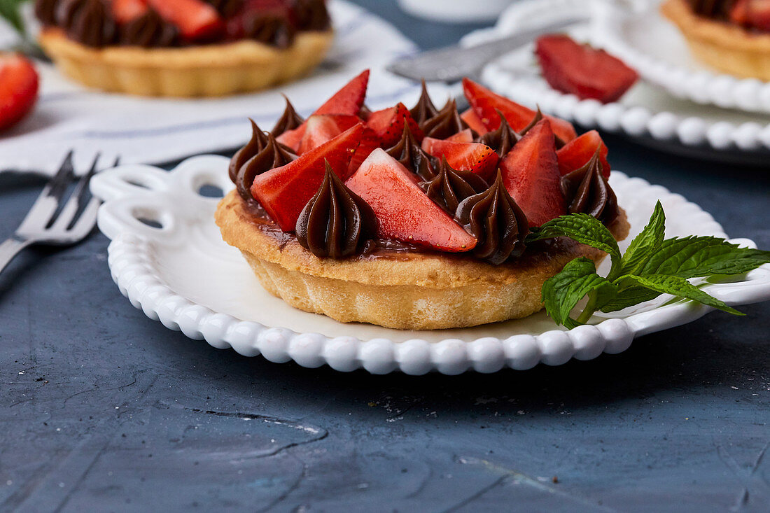 Mini tart with strawberry jam, served with fresh strawberries and chocolate ganache