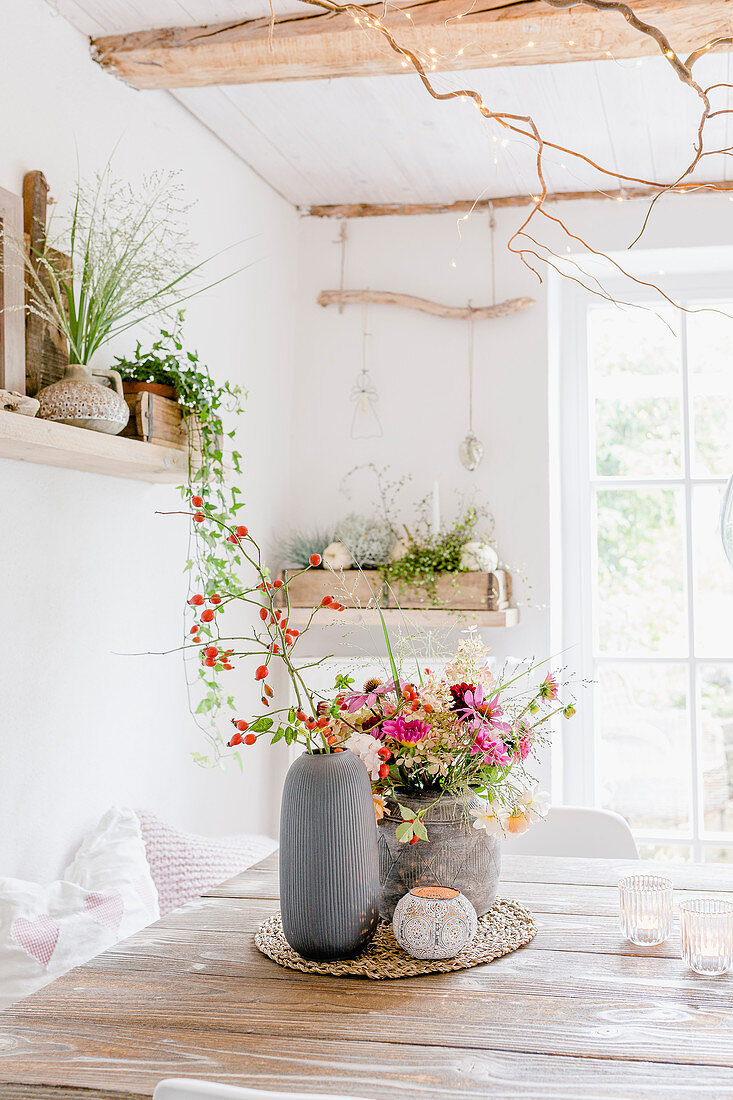 Autumn bouquet of dahlias, roses, rose hips, hydrangeas and grasses on dining table