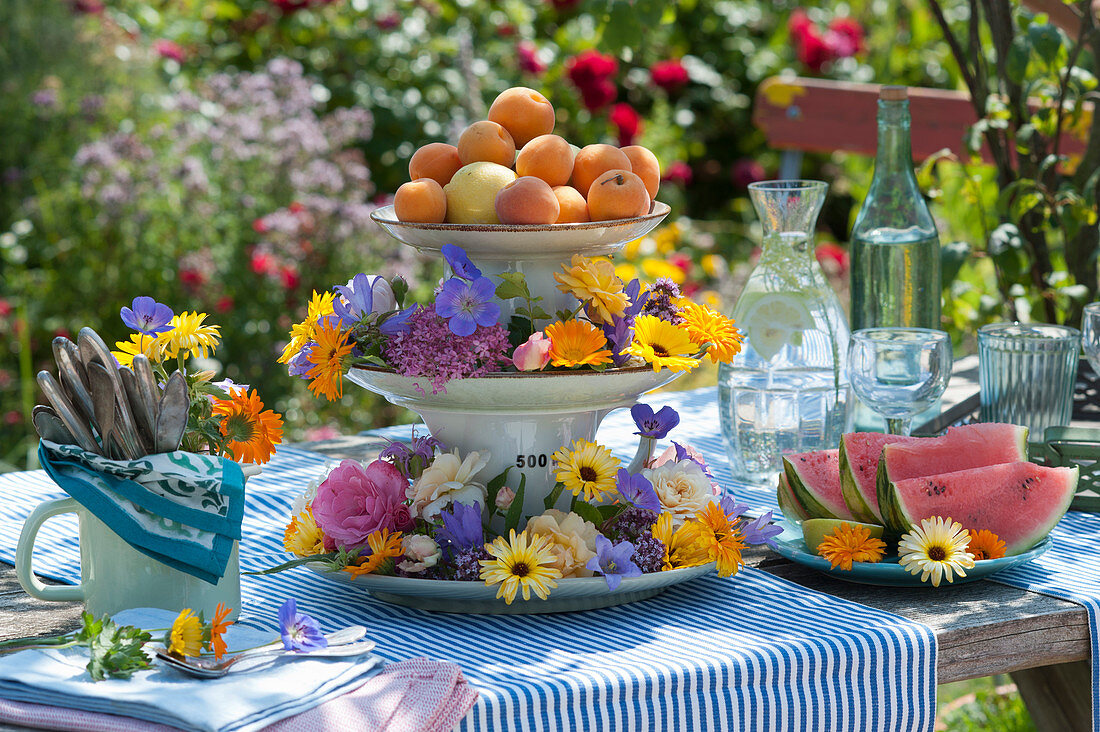 Cake stand with colourful flowers and apricots as table decoration
