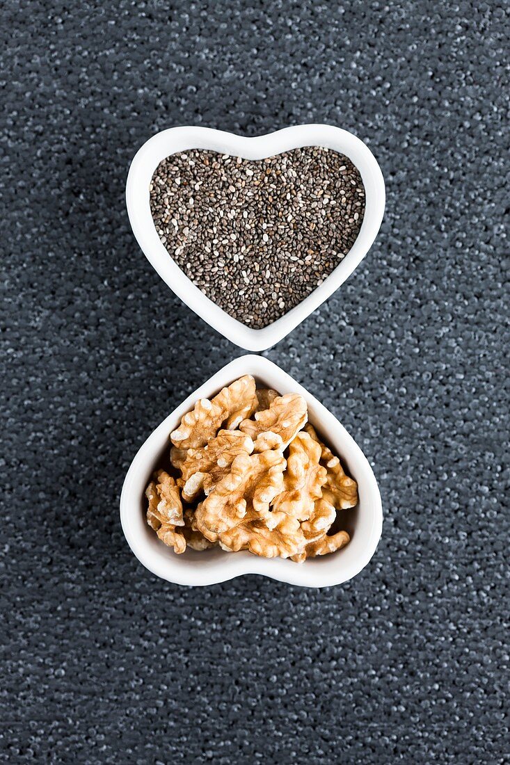 Black chia seeds and walnuts in heart shaped dish