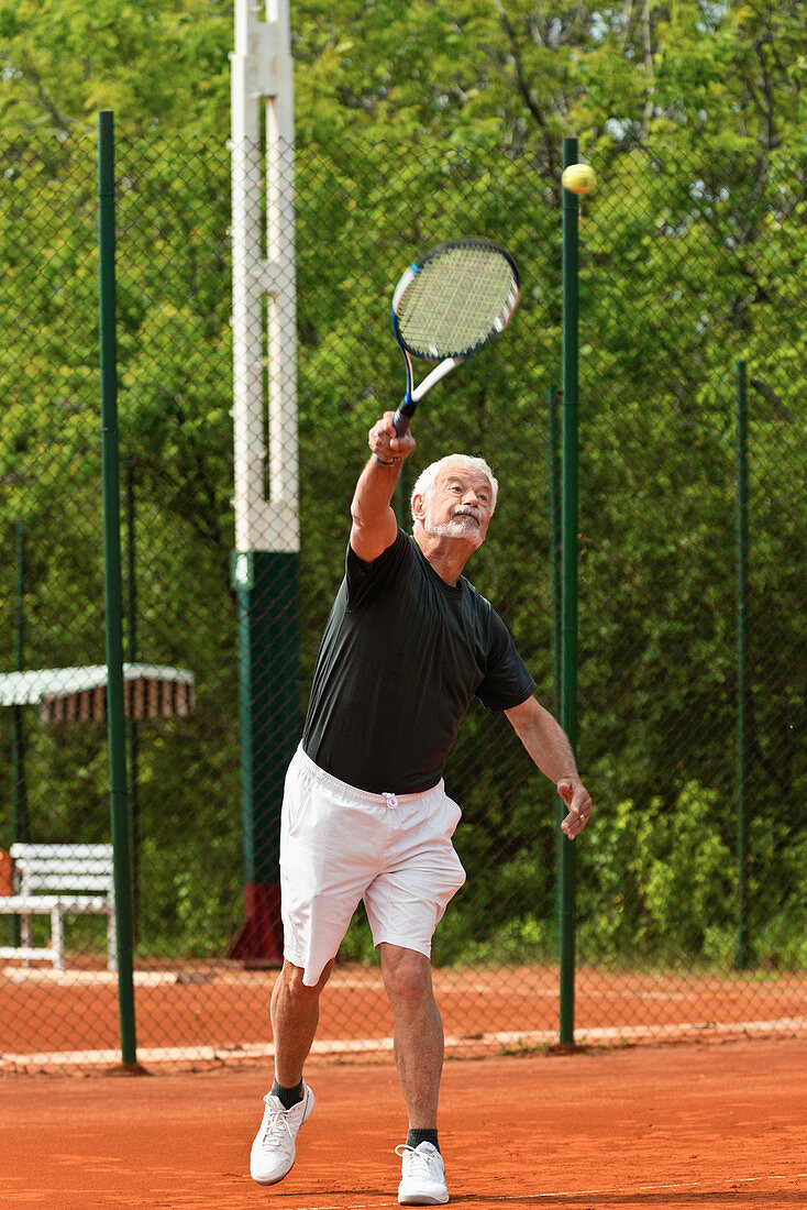 Senior male tennis player serving