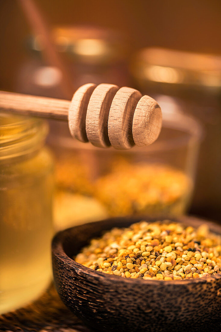 Honey dipper and honey bee pollen in wooden bowl
