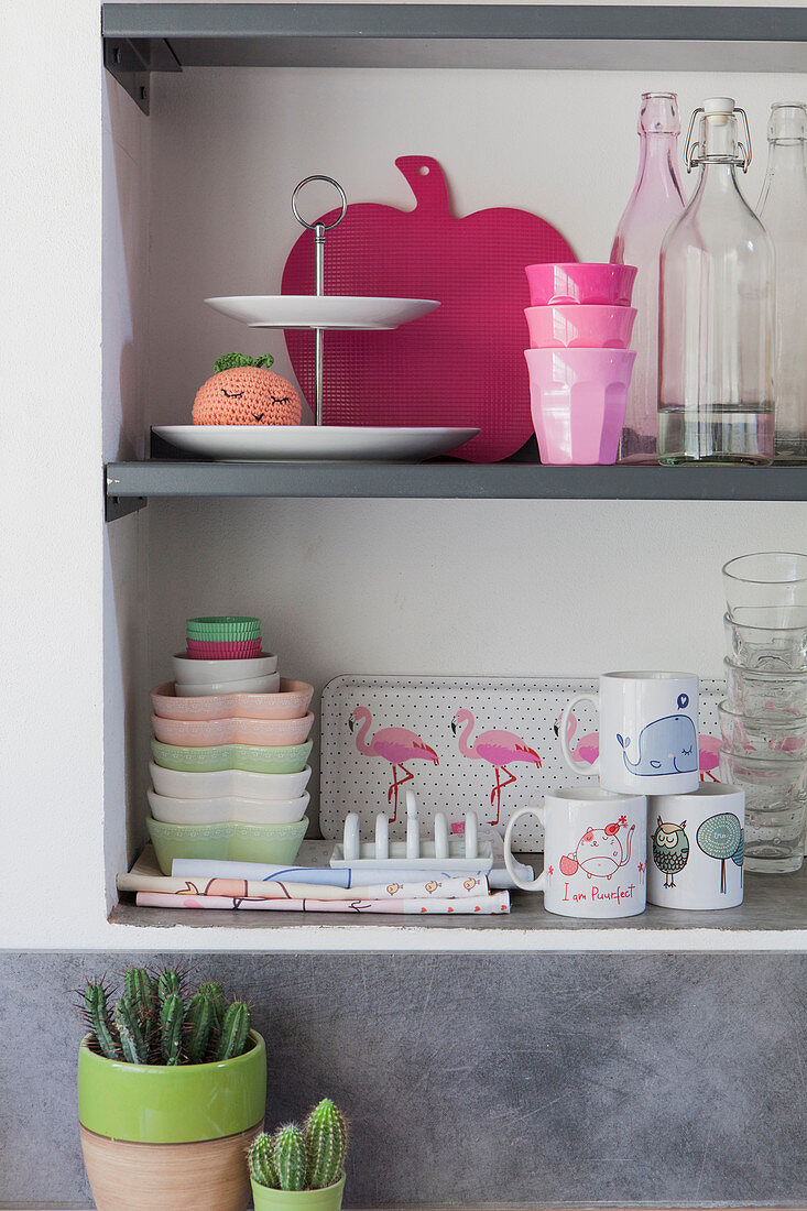 Feminine crockery and kitschy accessories on kitchen shelves