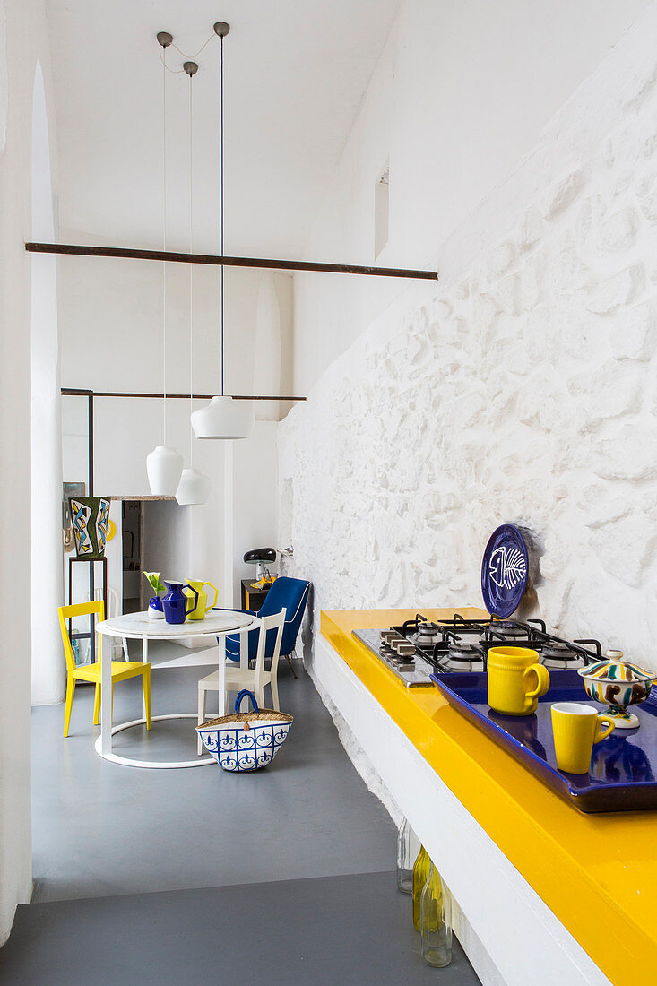 Open-plan kitchen and dining area with blue and yellow accents in Italian period building