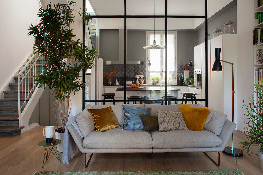 View past sofa in living area in kitchen separated by interior glass wall