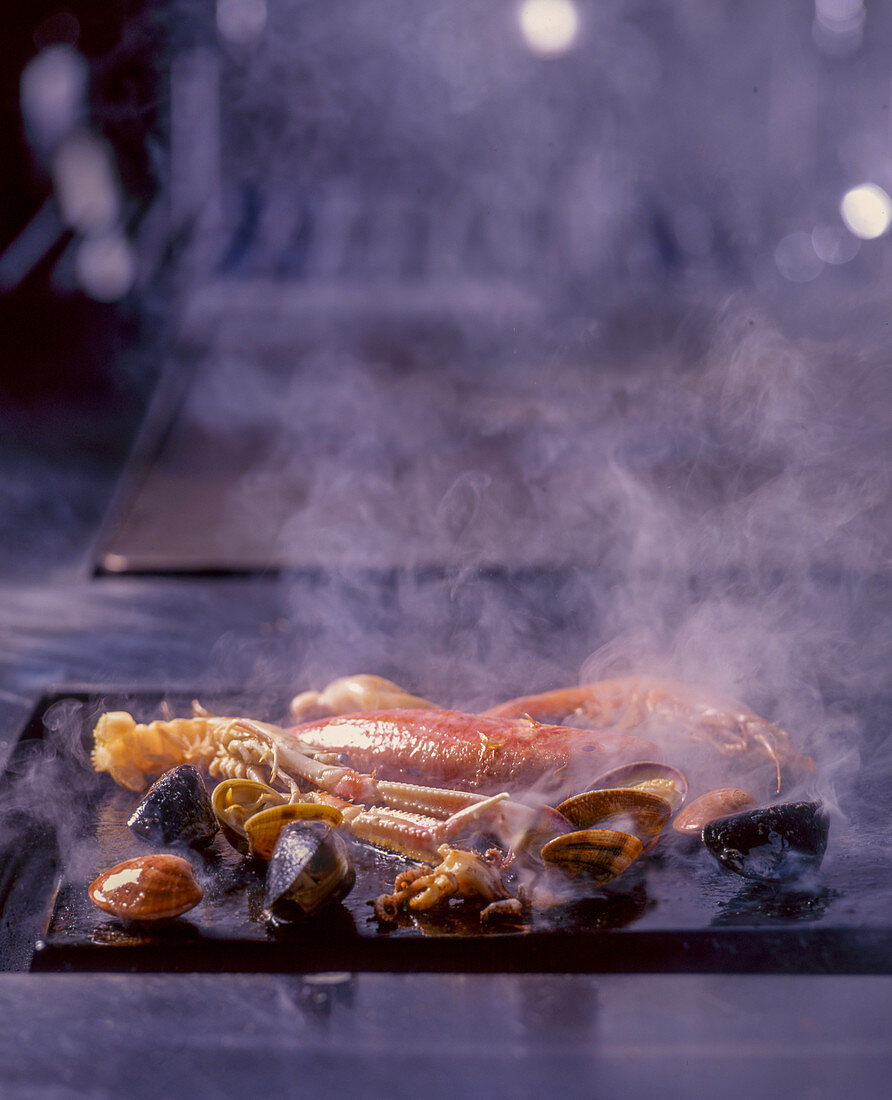 Fisch und Meeresfrüchte auf rauchender Grillplatte