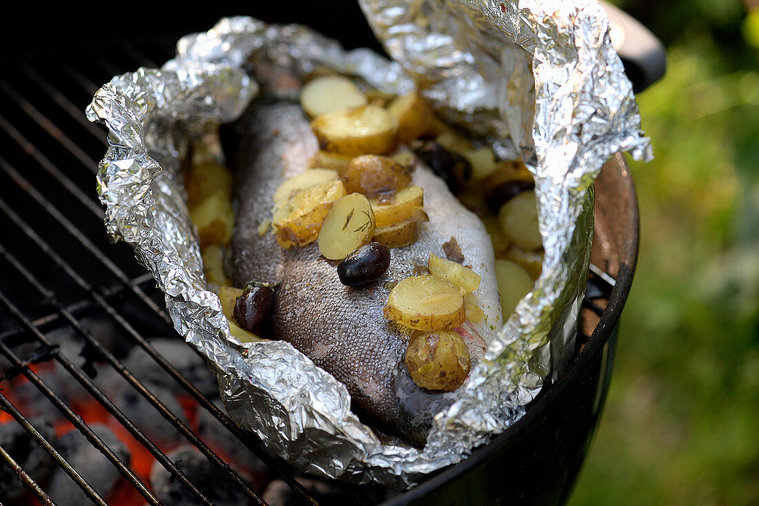 Bachschmerle mit Kartoffeln, Zitronen, Oliven und Salbeibutter in Alufolie