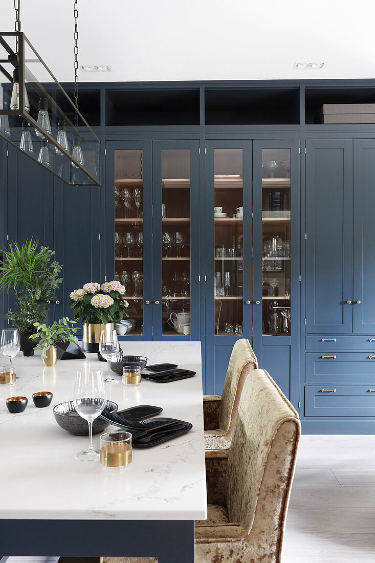 Gedeckter Tisch in Wohnküche mit blauen Fronten und Vitrinenschrank