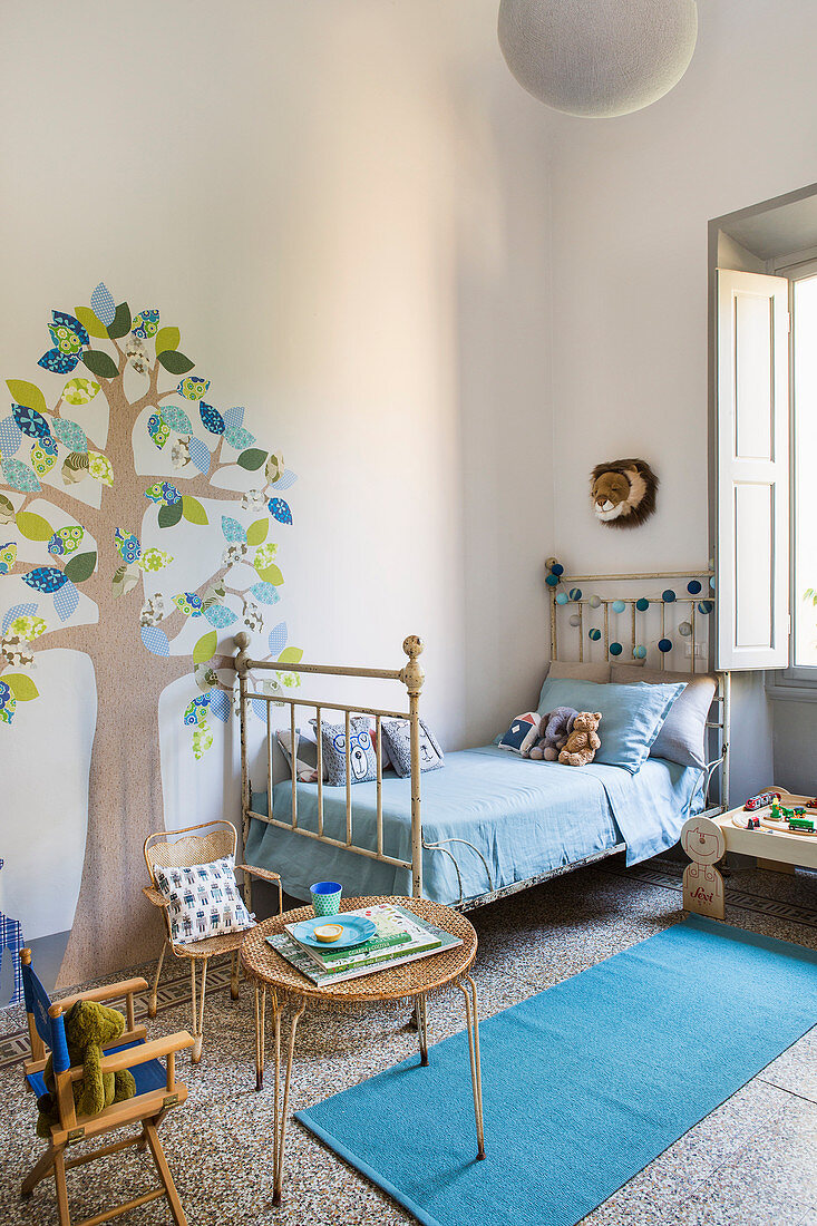 Vintage-style metal bed and tree motif painted on wall in child's bedroom in period apartment