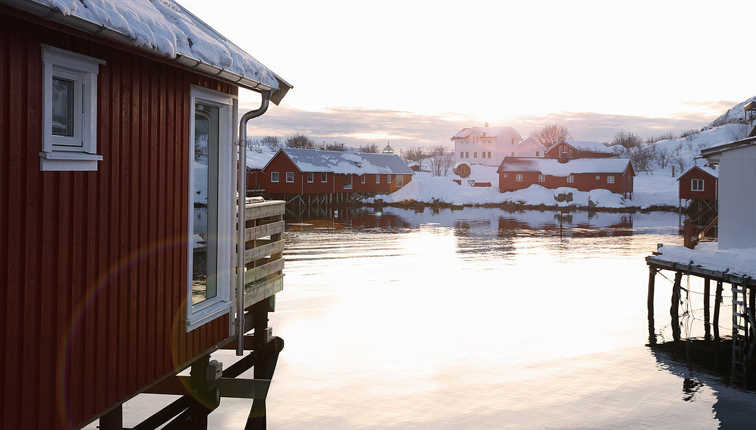 Houses with snowy roofs next to wintry Norwegian fjord