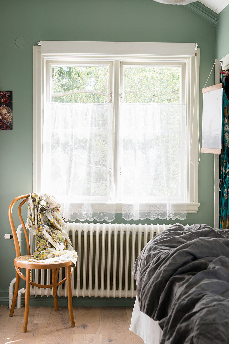 Bistrostuhl vorm Fenster mit Gardine im Schlafzimmer