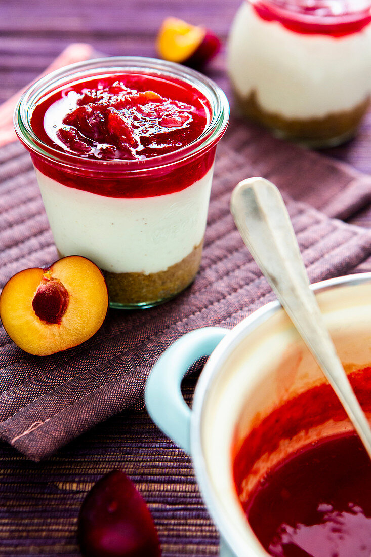 Layered desserts with cream cheese, plum compote and biscuit crumbs