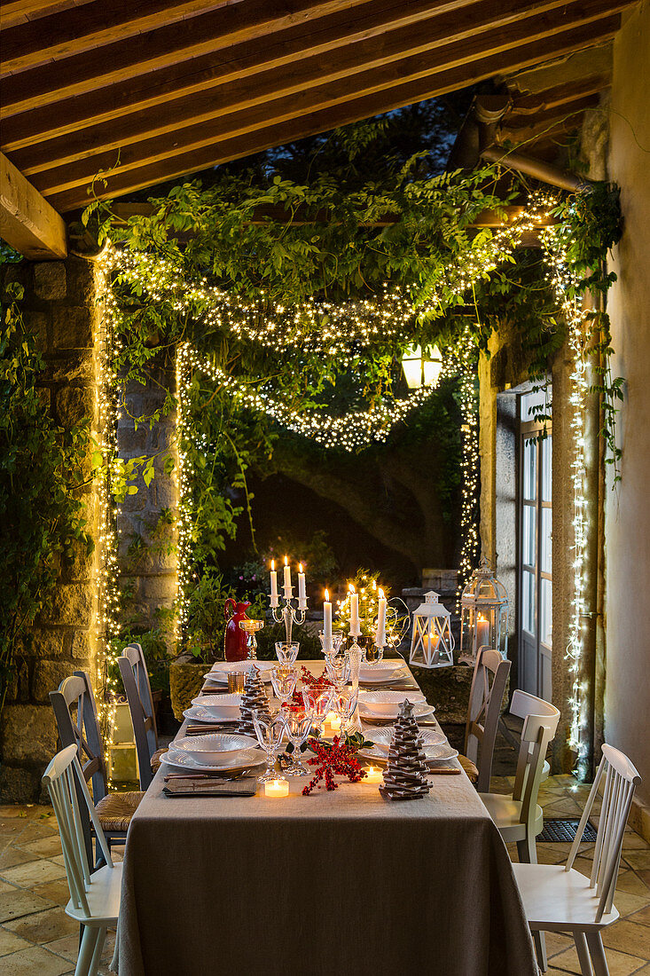 Festively decorated table on veranda lit by fairy lights