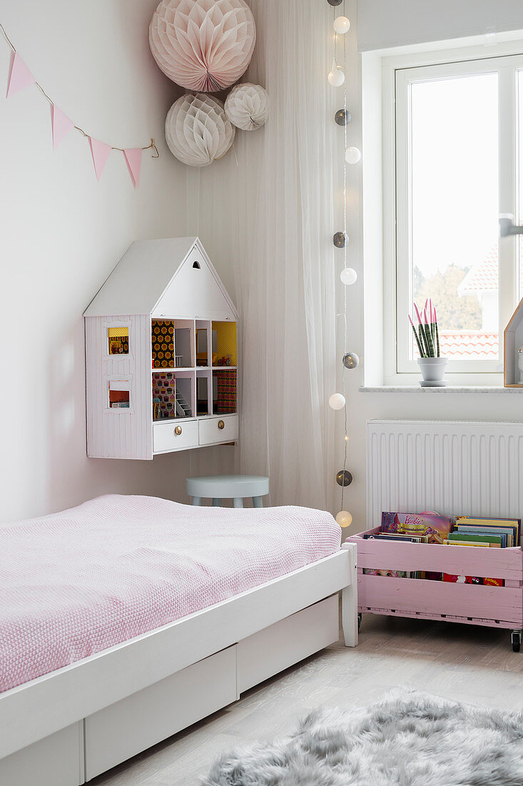 Dolls' house hung on wall in play area next to bed in girl's bedroom