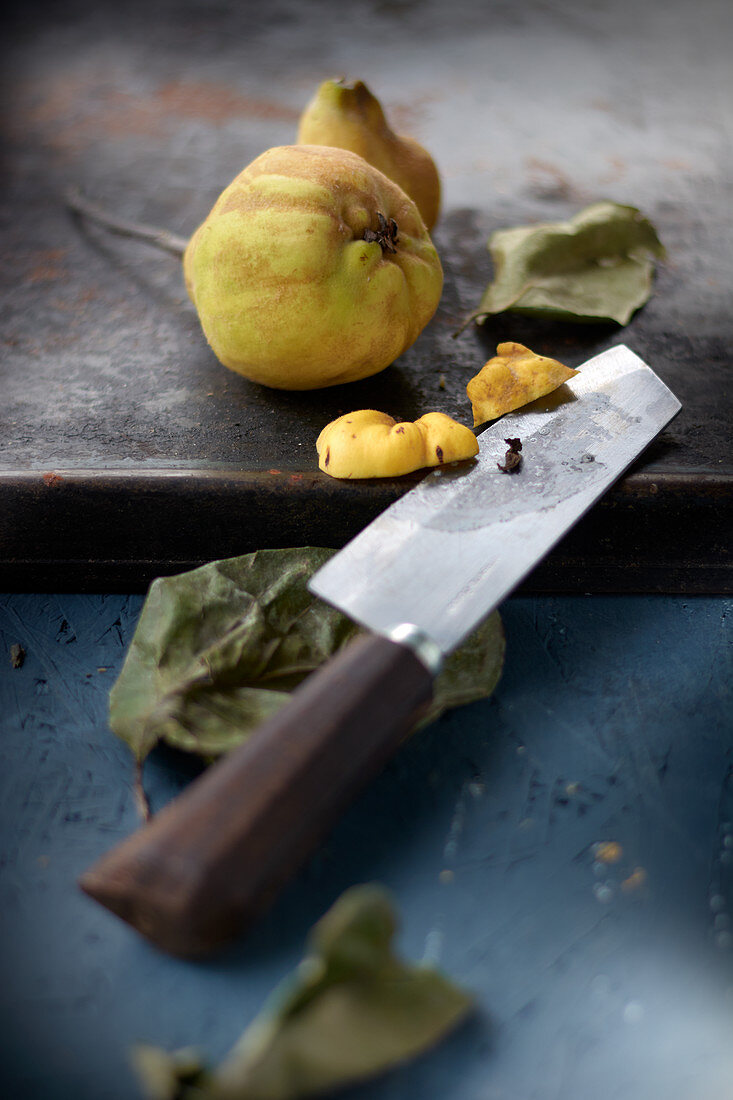 Quince on a wooden board with a chef's knife