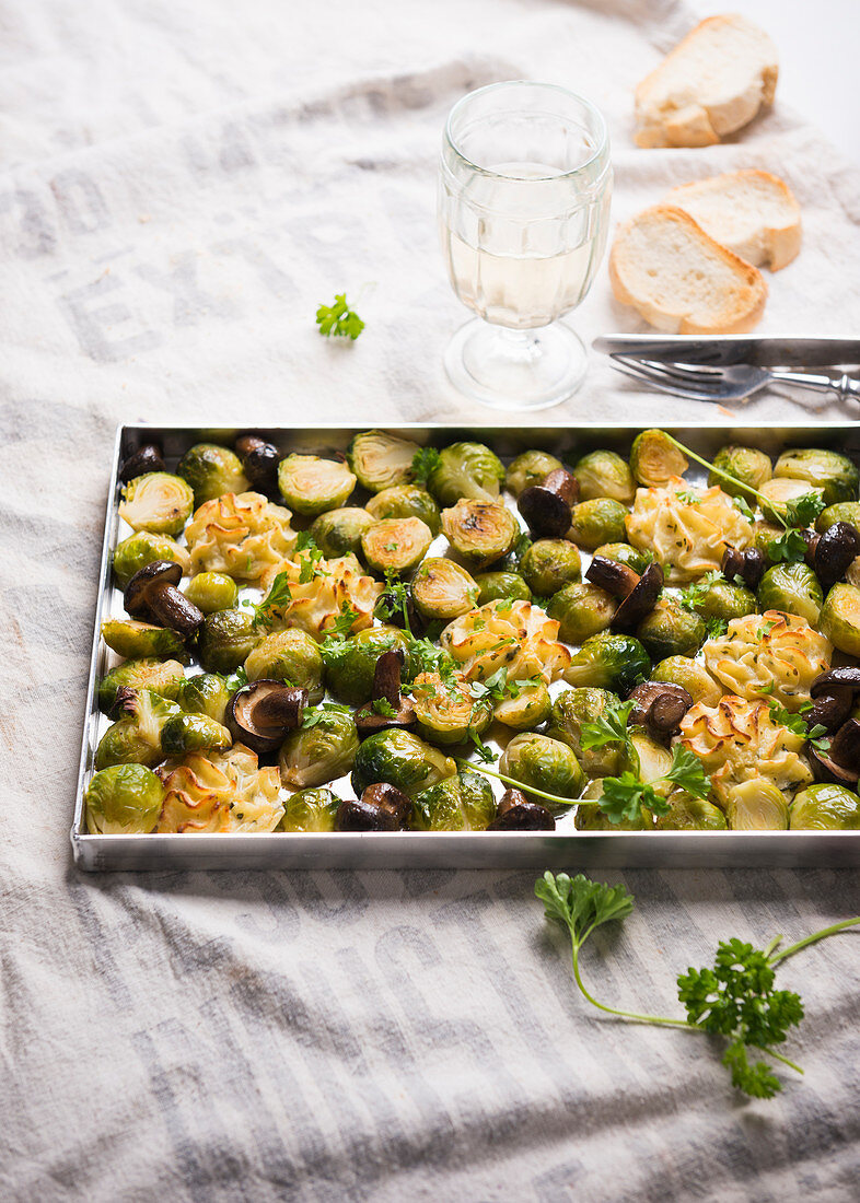 A baking tray with vegan duchess potatoes, baked brussels sprouts and wild mushrooms