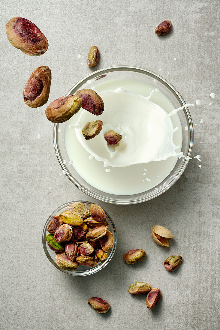 Pistachios falling into a glass of milk