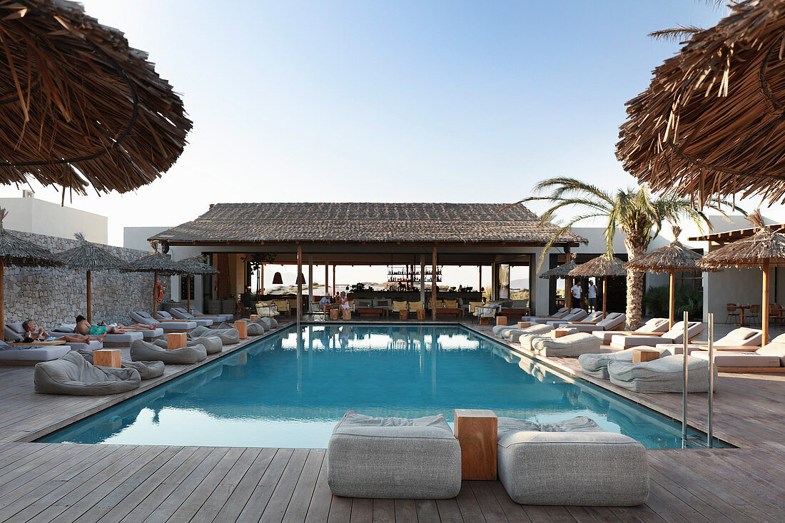 Pool surrounded by comfortable loungers on wooden deck