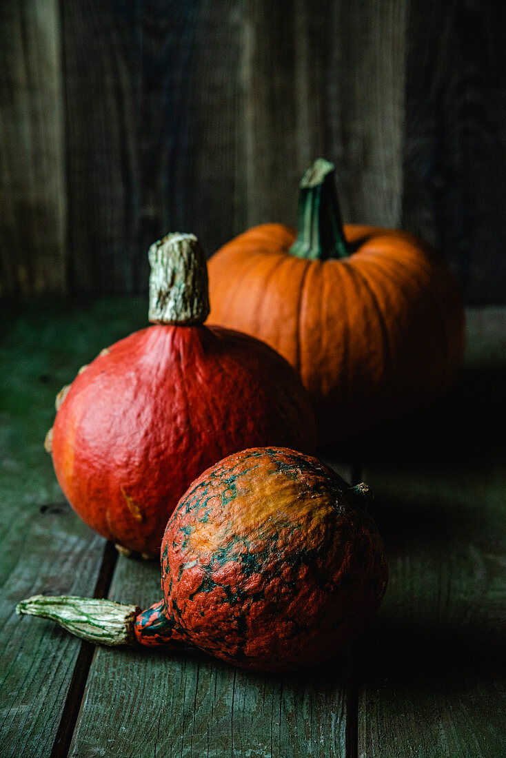 Three different pumpkins on a wooden background