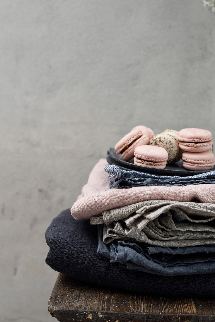 Two kinds of macarons on plates and stacked tablecloths