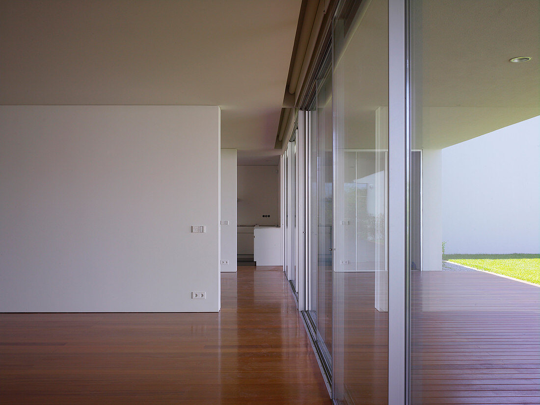 Durchgang entlang Trennwänden und Fensterfront in minimalistischem Wohnhaus