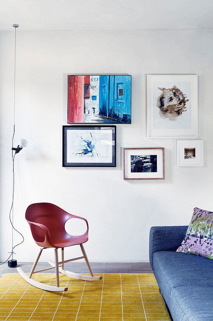 Designer rocking chair and couch next to small gallery of pictures in seating area