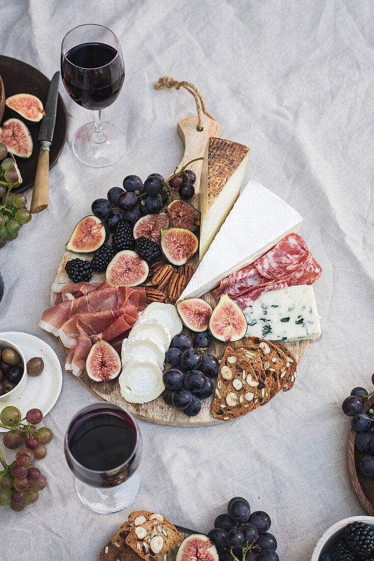 Käseplatte zum Picknick serviert mit Früchten, Nüssen und Rotwein