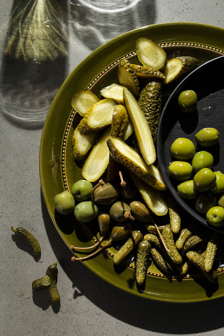 Essiggurken, Oliven und Kapern als Snack auf Servierteller