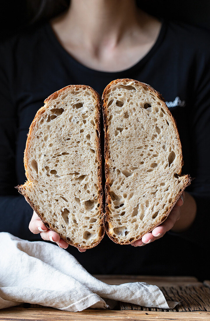 Frau hält halbiertes Kornbrot