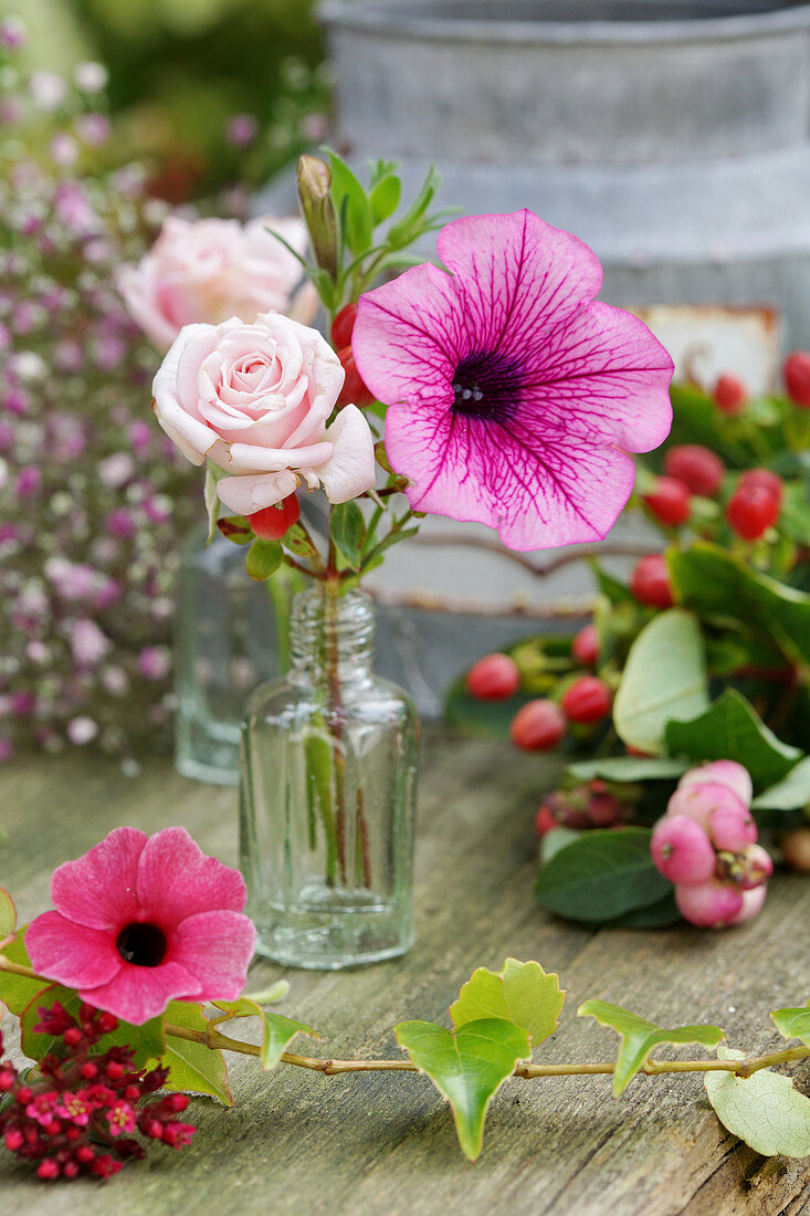 Rose and petunia flowers in a small bottle
