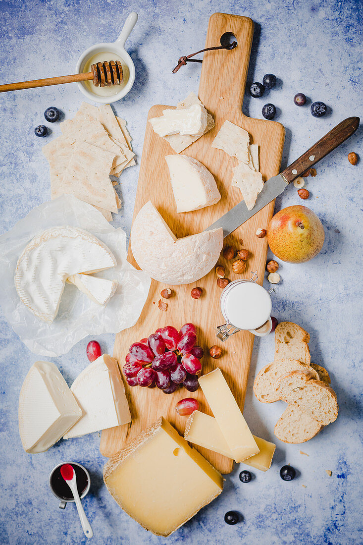 A cheese board with fruits, bread and honey