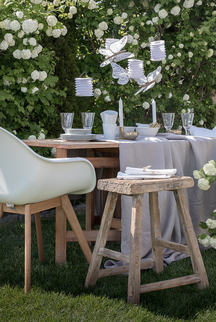 Gedeckter Tisch in Weiß und Beige im Garten vorm Schneeball-Strauch