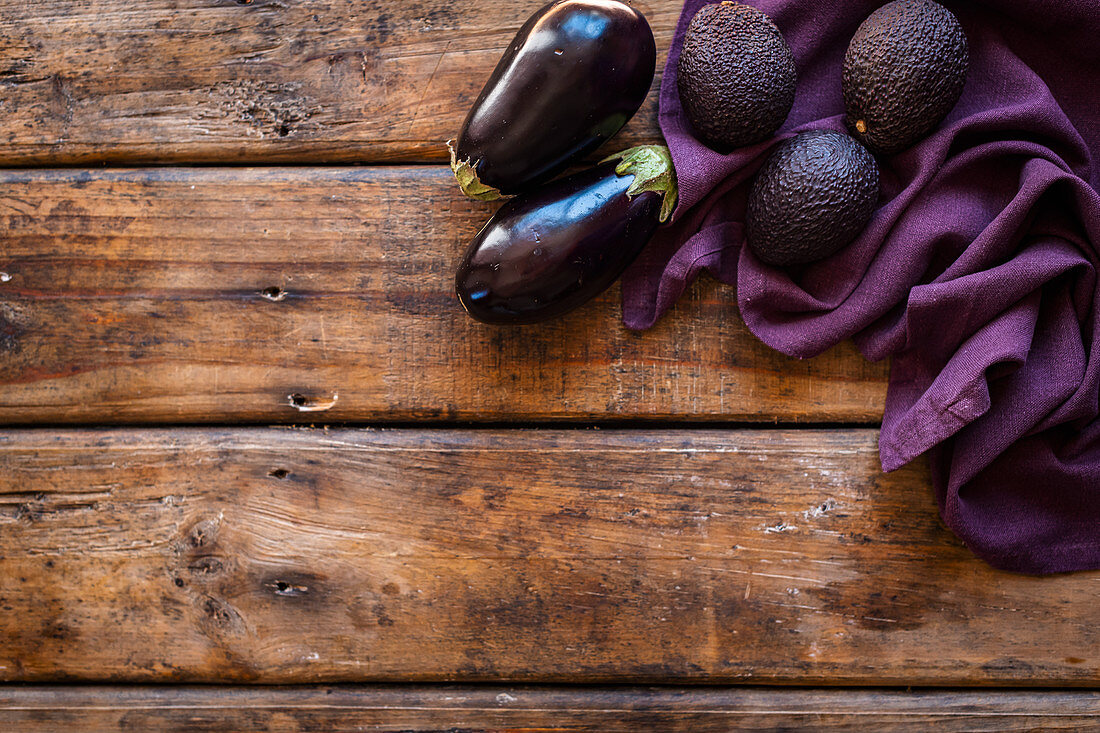 Lila Gemüse: Avocados und Auberginen auf violettem Tuch