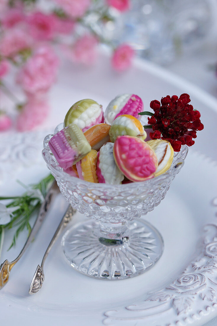 Colourful bonbons in a glass bowl decorated with a flower