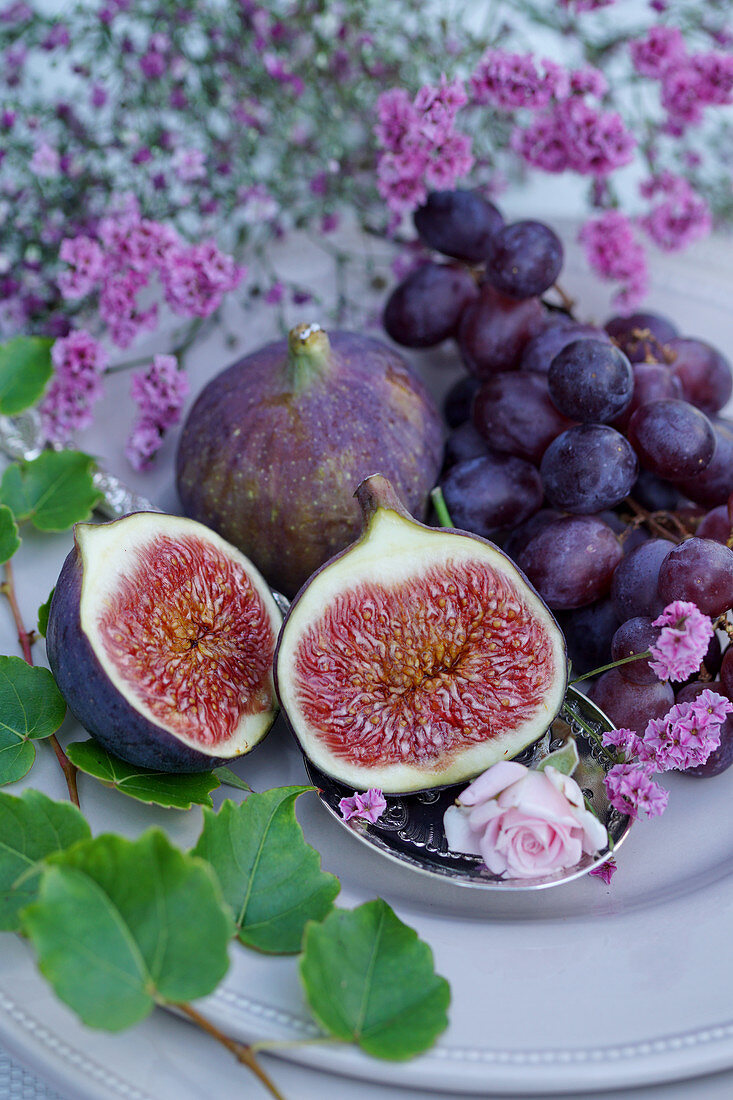 Fresh figs and grapes surrounded by flowers