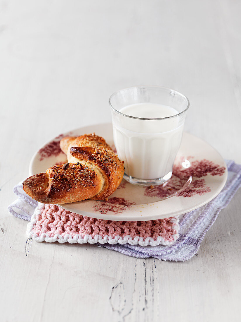 Ein Croissant serviert mit einem Glas Milch