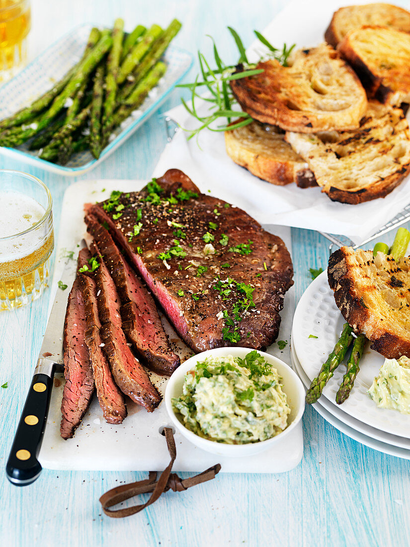 Barbeque flank steak with asparagus, herb butter and grilled bread